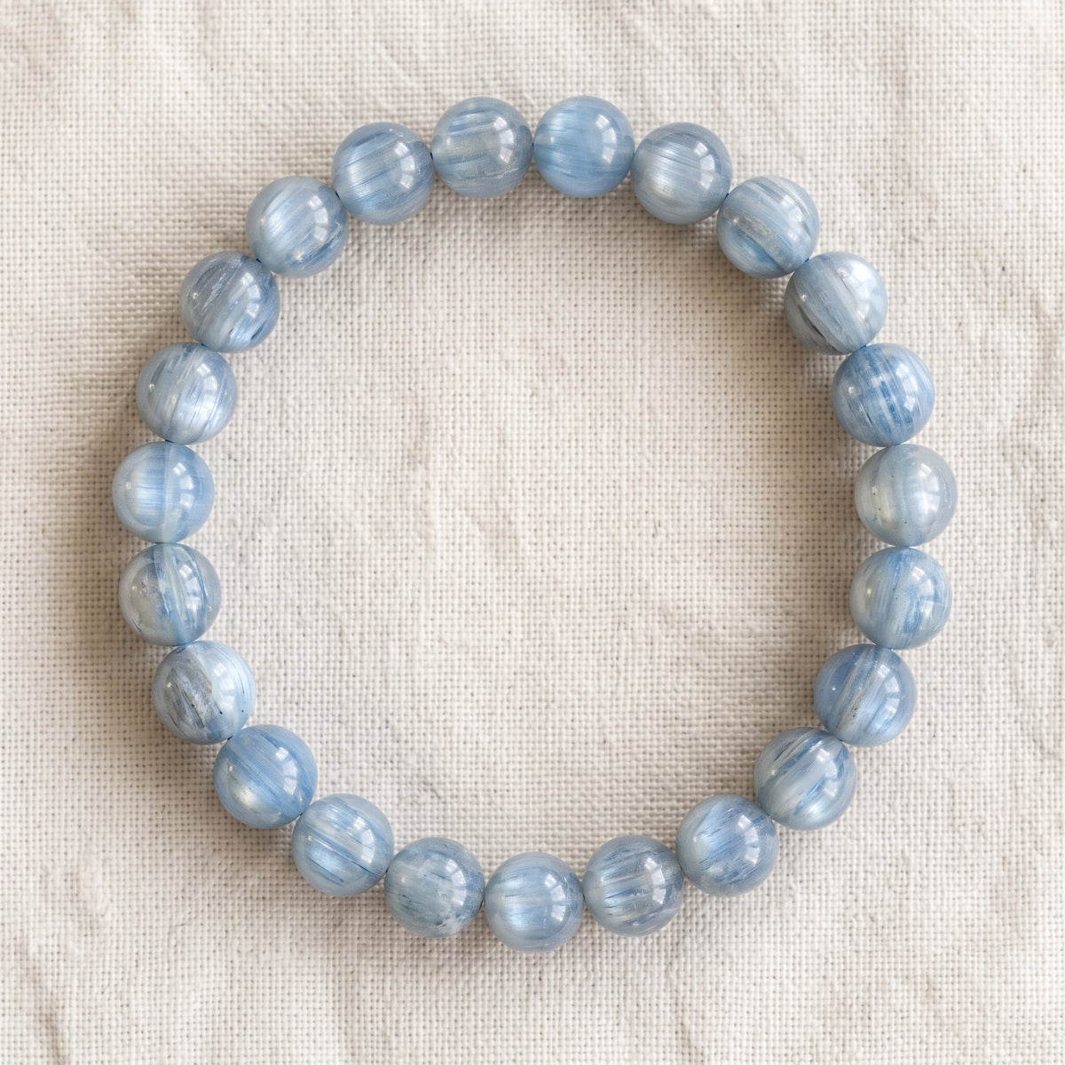 Bracelet en cyanite : perles rondes de pierre naturelle de 8 mm sur elastique, sans interperle (variante temporaire), vu de dessus sur du lin ivoire - visuel provisoire