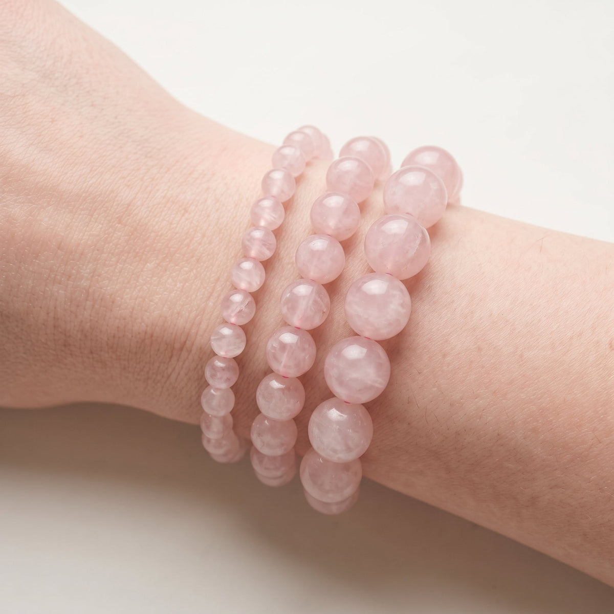 Trois bracelets en quartz rose de diamètres différents, portés ensemble au poignet - visuel provisoire