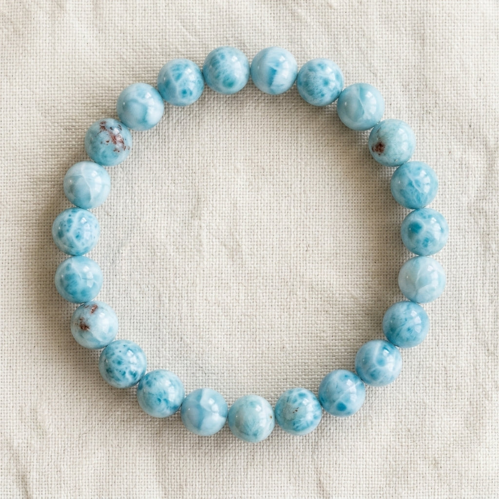 Bracelet en larimar : perles rondes de pierre naturelle de 8 mm sur elastique, sans interperle (variante temporaire), vu de dessus sur du lin ivoire - visuel provisoire