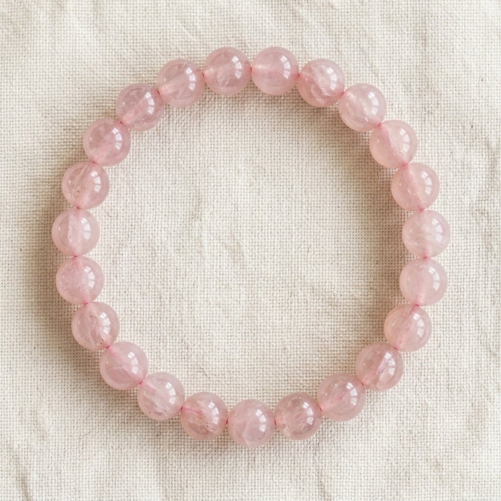 Bracelet en quartz rose : perles rondes de pierre naturelle de 8 mm sur elastique, sans interperle (variante temporaire), vu de dessus sur du lin ivoire - visuel provisoire