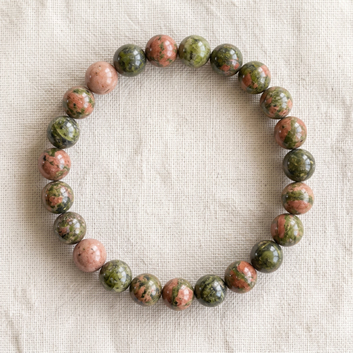 Bracelet en unakite : perles rondes de pierre naturelle de 8 mm sur elastique, sans interperle (variante temporaire), vu de dessus sur du lin ivoire - visuel provisoire