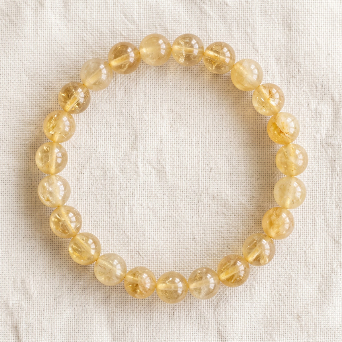Bracelet en citrine : perles rondes de pierre naturelle de 8 mm sur elastique, sans interperle (variante temporaire), vu de dessus sur du lin ivoire - visuel provisoire