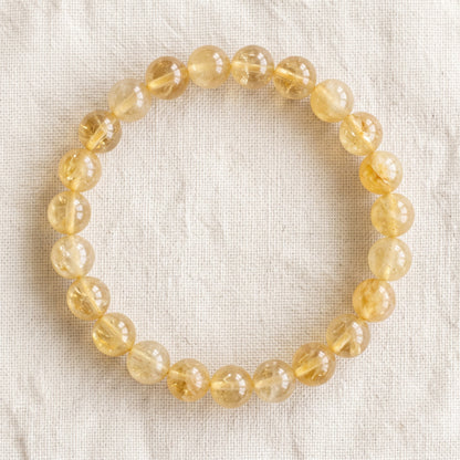 Bracelet en citrine : perles rondes de pierre naturelle de 8 mm sur elastique, sans interperle (variante temporaire), vu de dessus sur du lin ivoire - visuel provisoire