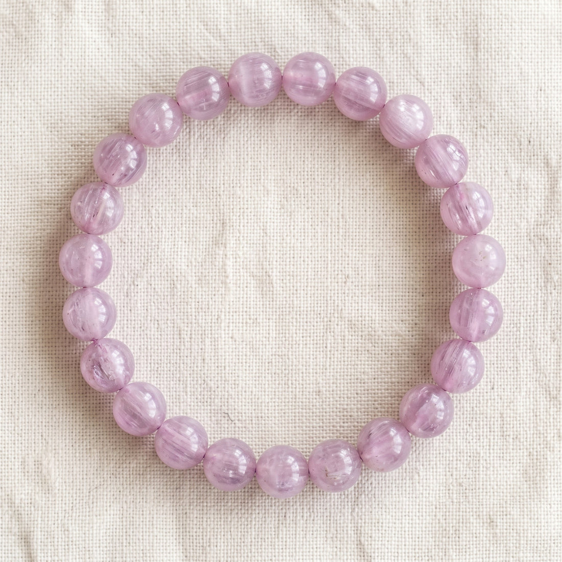 Bracelet en kunzite : perles rondes de pierre naturelle de 8 mm sur elastique, sans interperle (variante temporaire), vu de dessus sur du lin ivoire - visuel provisoire