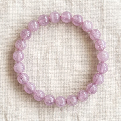 Bracelet en kunzite : perles rondes de pierre naturelle de 8 mm sur elastique, sans interperle (variante temporaire), vu de dessus sur du lin ivoire - visuel provisoire