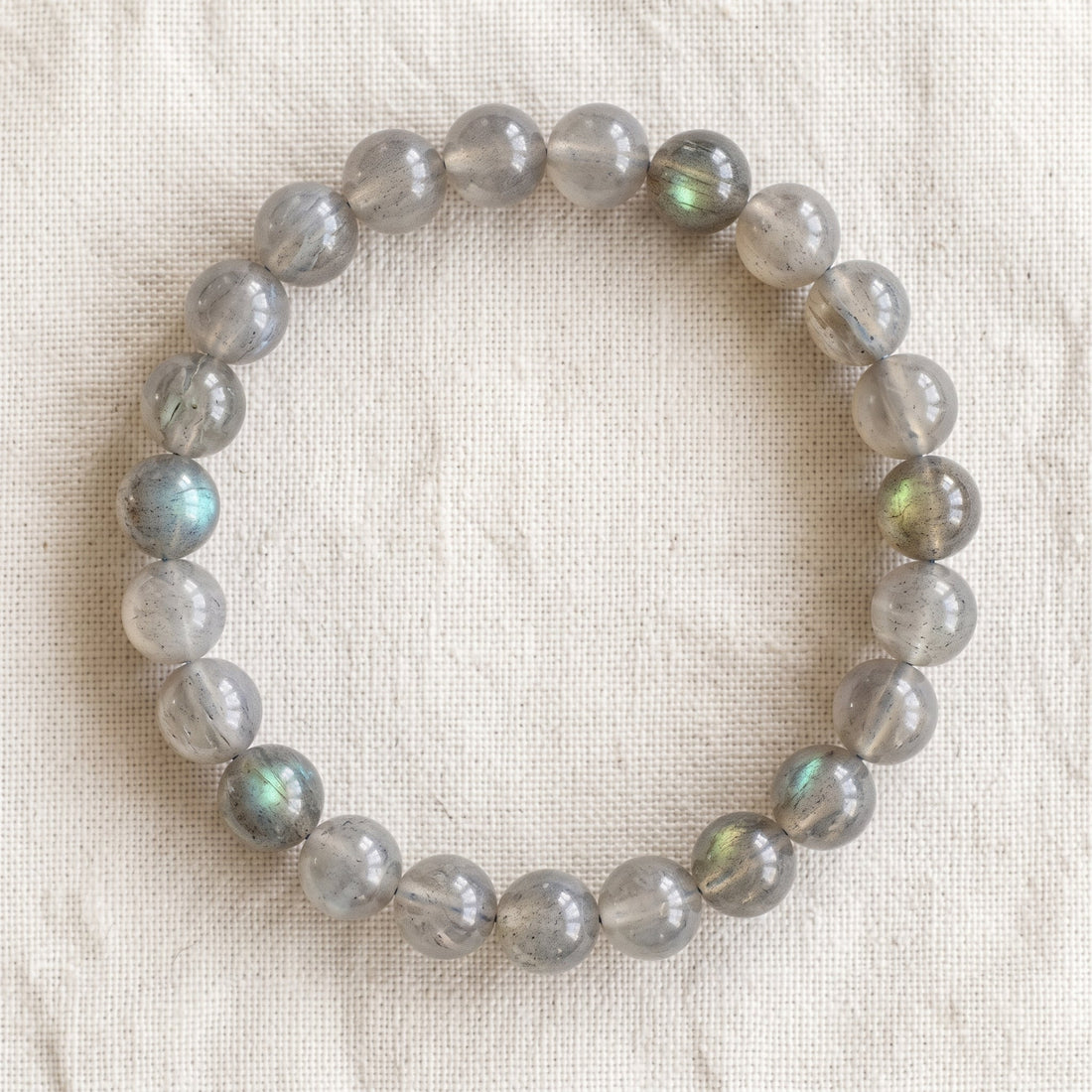 Bracelet en labradorite : perles rondes de pierre naturelle de 8 mm sur elastique, sans interperle (variante temporaire), vu de dessus sur du lin ivoire - visuel provisoire