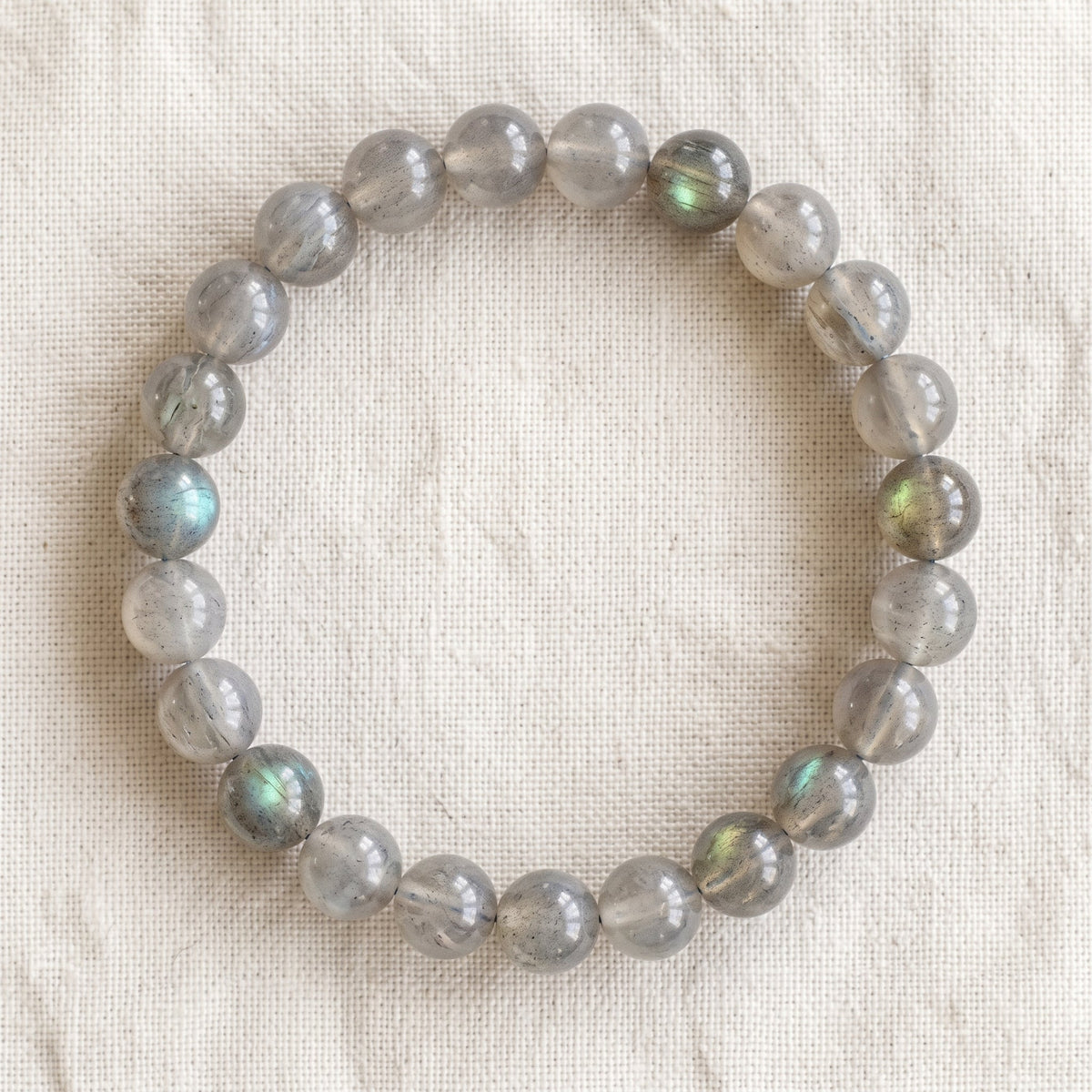 Bracelet en labradorite : perles rondes de pierre naturelle de 8 mm sur elastique, sans interperle (variante temporaire), vu de dessus sur du lin ivoire - visuel provisoire