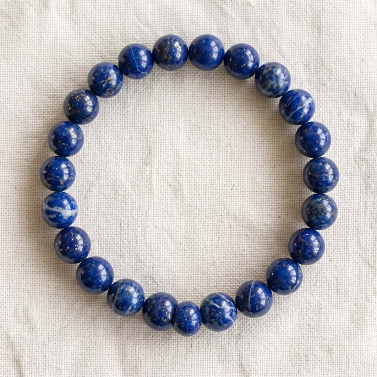 Bracelet en lapis lazuli : perles rondes de pierre naturelle de 8 mm sur elastique, sans interperle (variante temporaire), vu de dessus sur du lin ivoire - visuel provisoire
