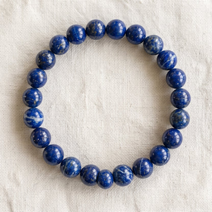 Bracelet en lapis lazuli : perles rondes de pierre naturelle de 8 mm sur elastique, sans interperle (variante temporaire), vu de dessus sur du lin ivoire - visuel provisoire