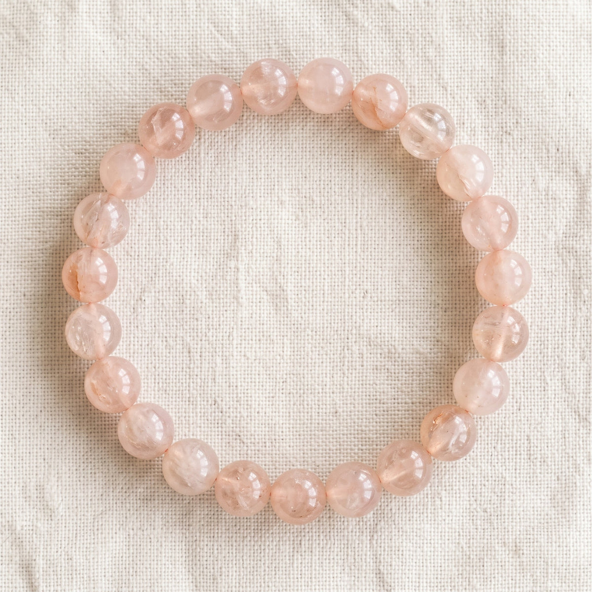 Bracelet en morganite : perles rondes de pierre naturelle de 8 mm sur elastique, sans interperle (variante temporaire), vu de dessus sur du lin ivoire - visuel provisoire