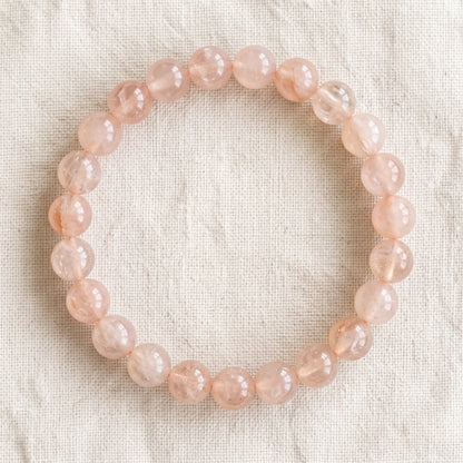 Bracelet en morganite : perles rondes de pierre naturelle de 8 mm sur elastique, sans interperle (variante temporaire), vu de dessus sur du lin ivoire - visuel provisoire