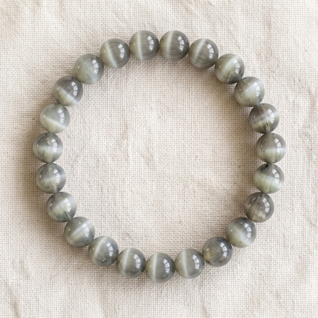 Bracelet en oeil de chat : perles rondes de pierre naturelle de 8 mm sur elastique, sans interperle (variante temporaire), vu de dessus sur du lin ivoire - visuel provisoire