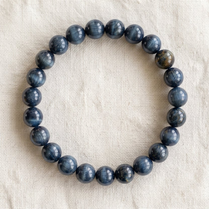 Bracelet en oeil de faucon : perles rondes de pierre naturelle de 8 mm sur elastique, sans interperle (variante temporaire), vu de dessus sur du lin ivoire - visuel provisoire