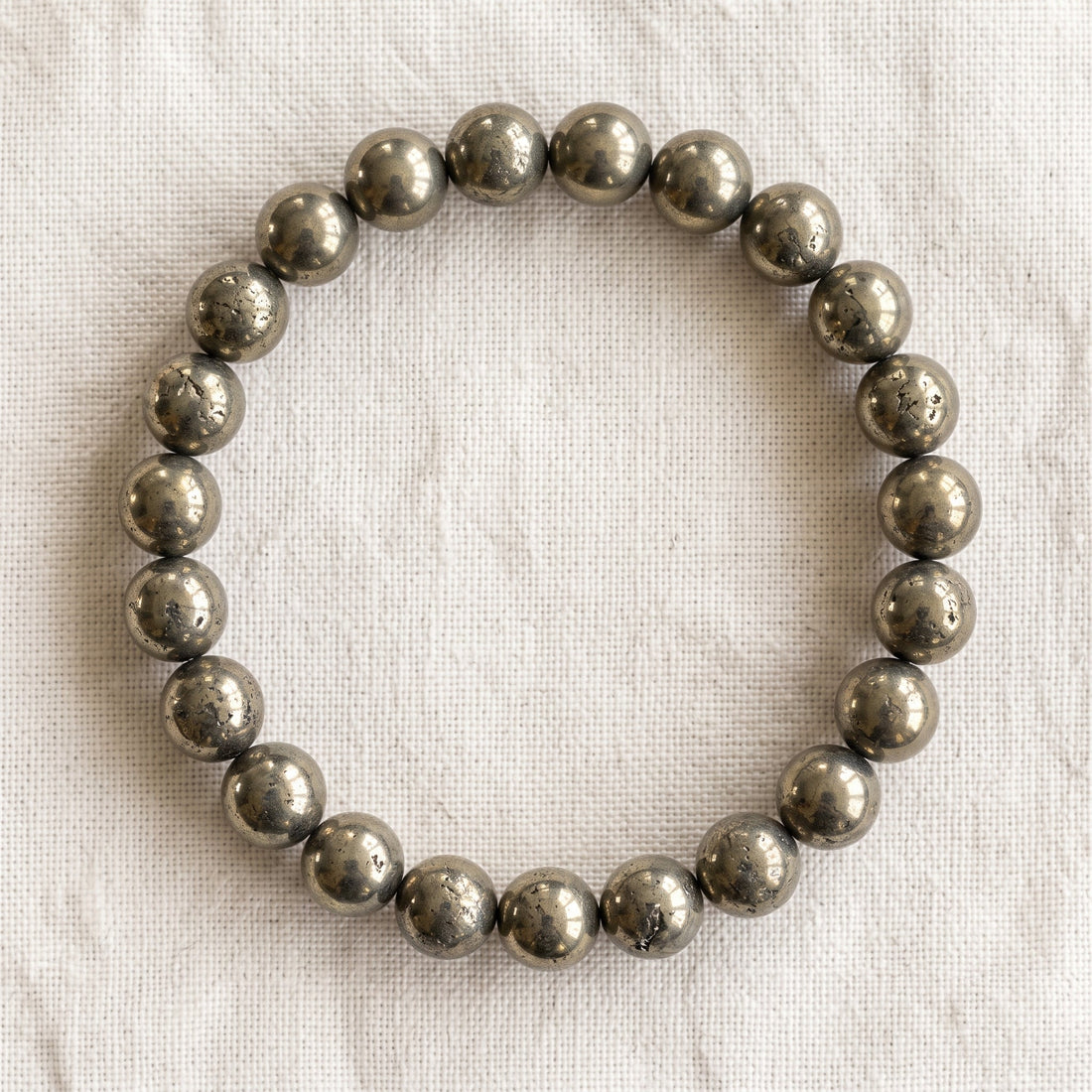 Bracelet en pyrite : perles rondes de pierre naturelle de 8 mm sur elastique, sans interperle (variante temporaire), vu de dessus sur du lin ivoire - visuel provisoire