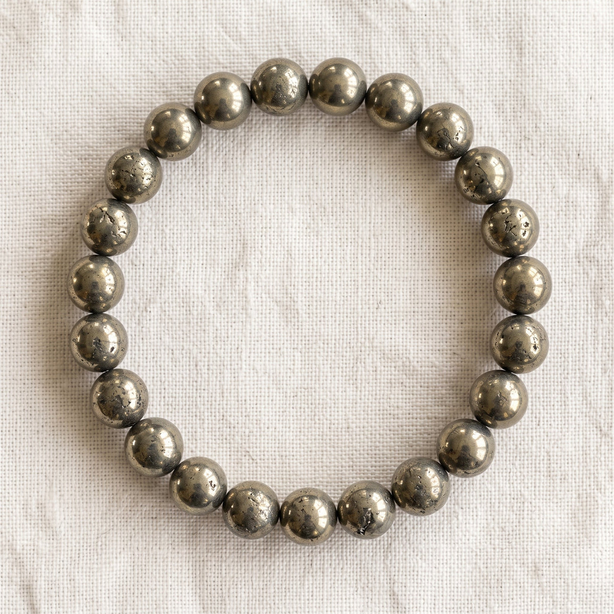 Bracelet en pyrite : perles rondes de pierre naturelle de 8 mm sur elastique, sans interperle (variante temporaire), vu de dessus sur du lin ivoire - visuel provisoire