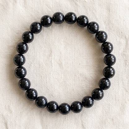 Bracelet en tourmaline noire : perles rondes de pierre naturelle de 8 mm sur elastique, sans interperle (variante temporaire), vu de dessus sur du lin ivoire - visuel provisoire