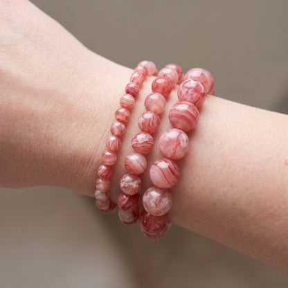 Trois bracelets en agate cerise de diamètres différents, portés ensemble au poignet - visuel provisoire