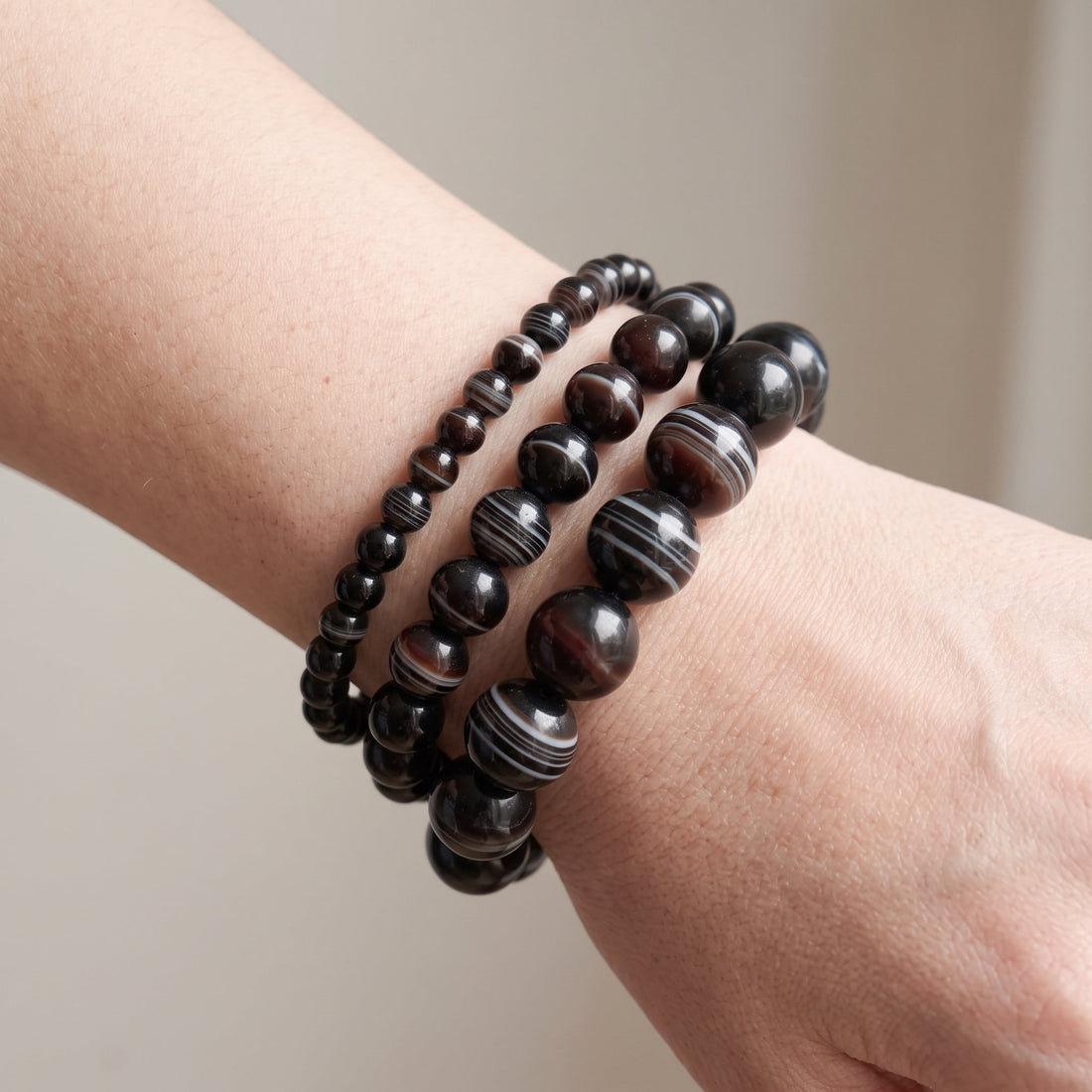 Trois bracelets en agate sardonyx de diamètres différents, portés ensemble au poignet - visuel provisoire