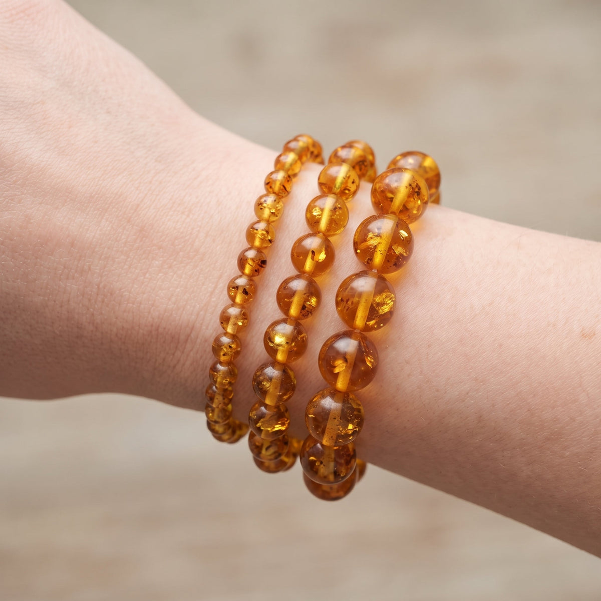 Trois bracelets en ambre de diamètres différents, portés ensemble au poignet - visuel provisoire