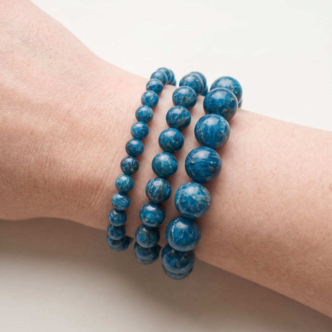 Trois bracelets en apatite bleue de diamètres différents, portés ensemble au poignet - visuel provisoire