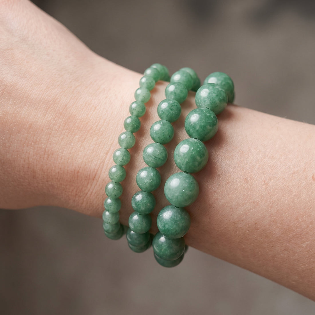 Trois bracelets en aventurine verte de diamètres différents, portés ensemble au poignet - visuel provisoire