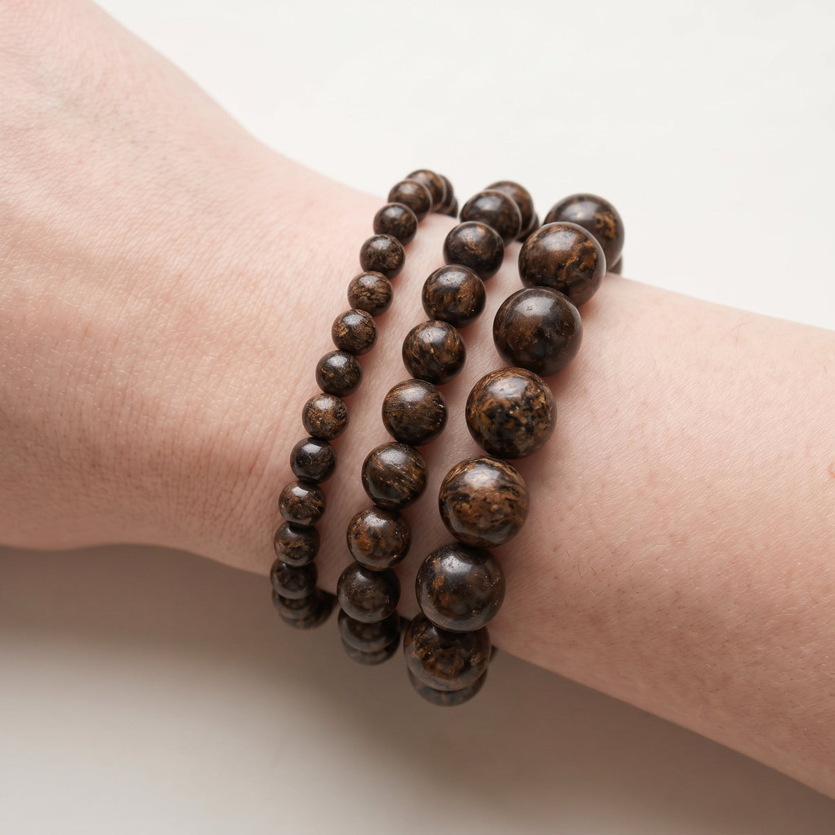 Trois bracelets en bronzite de diamètres différents, portés ensemble au poignet - visuel provisoire