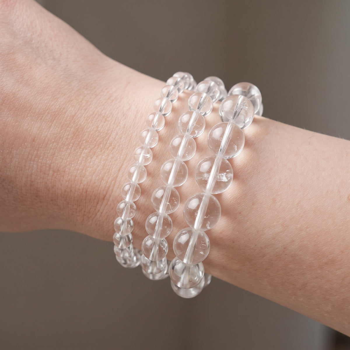Trois bracelets en cristal de roche craquelé de diamètres différents, portés ensemble au poignet - visuel provisoire