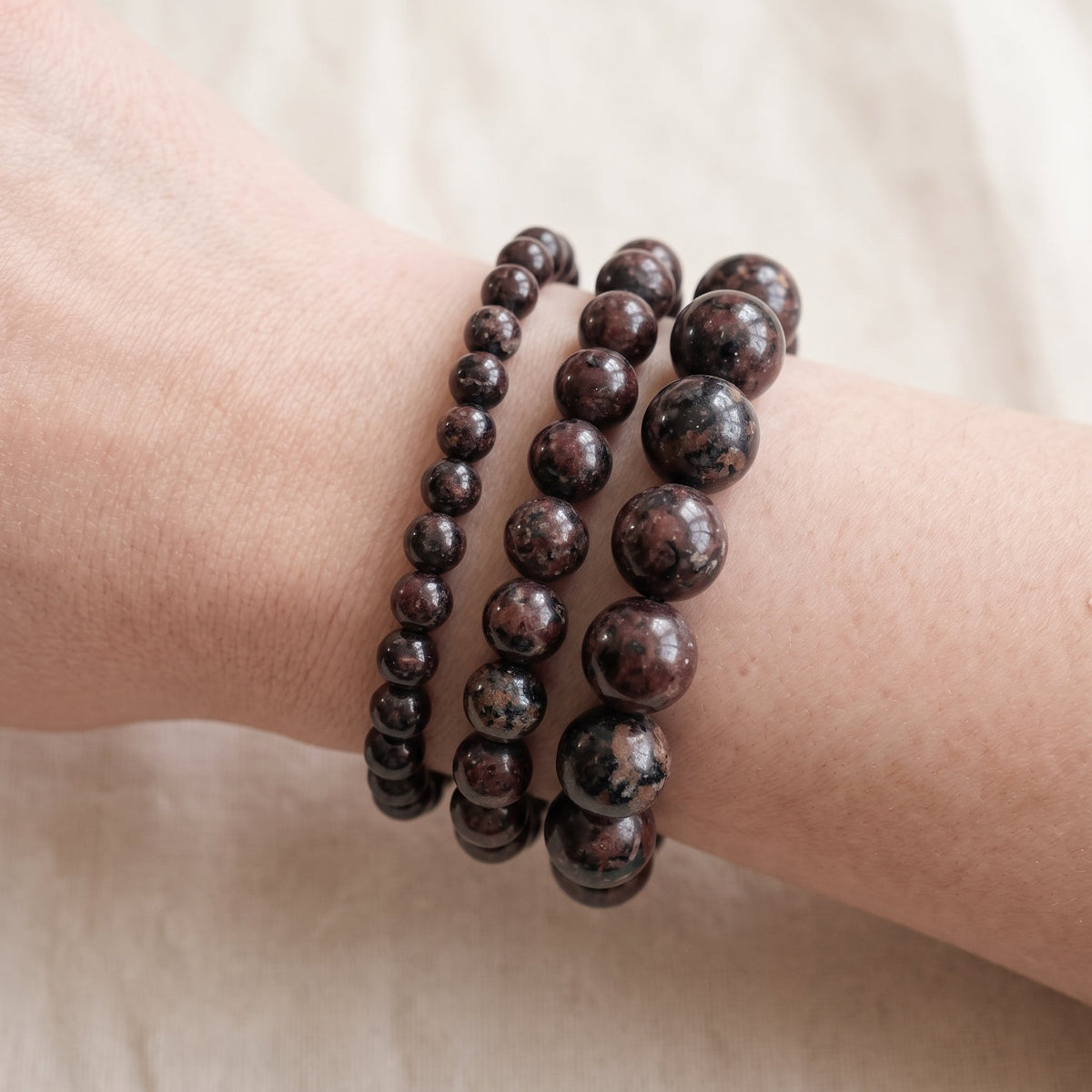 Trois bracelets en eudialyte de diamètres différents, portés ensemble au poignet - visuel provisoire