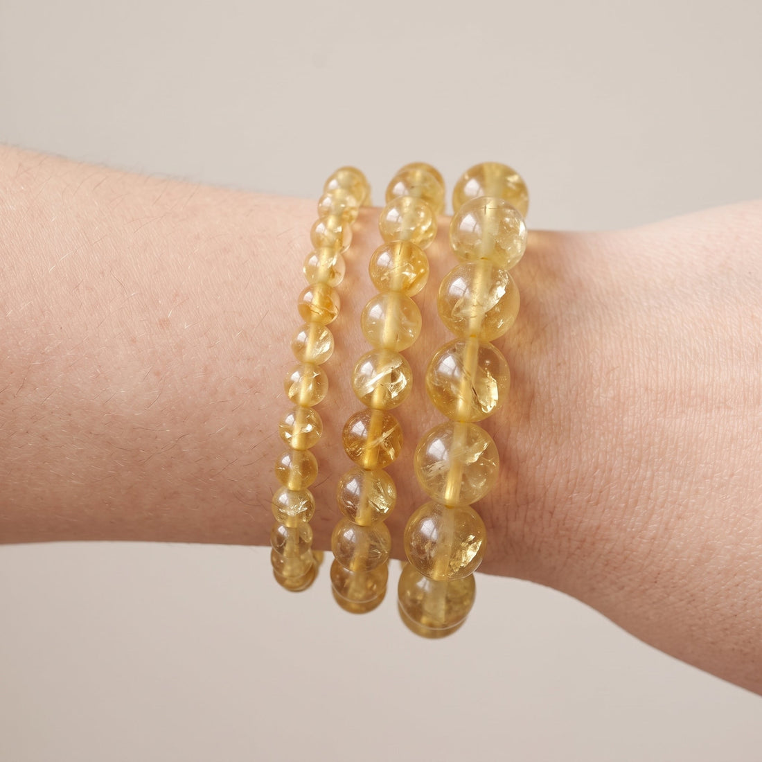 Trois bracelets en fluorite jaune de diamètres différents, portés ensemble au poignet - visuel provisoire