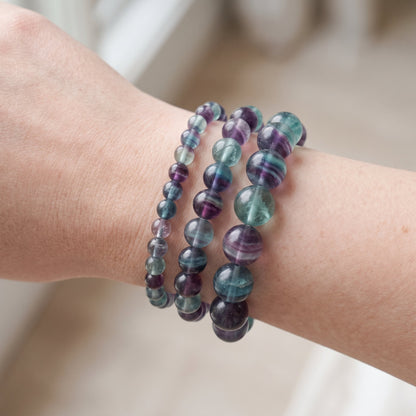 Trois bracelets en fluorite de diamètres différents, portés ensemble au poignet - visuel provisoire