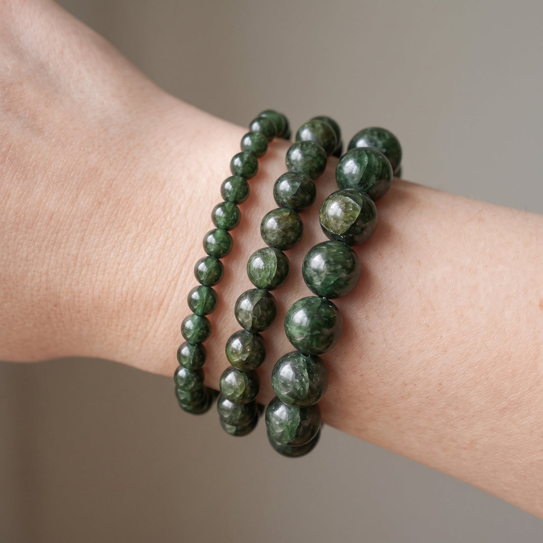 Trois bracelets en grenat vert de diamètres différents, portés ensemble au poignet - visuel provisoire