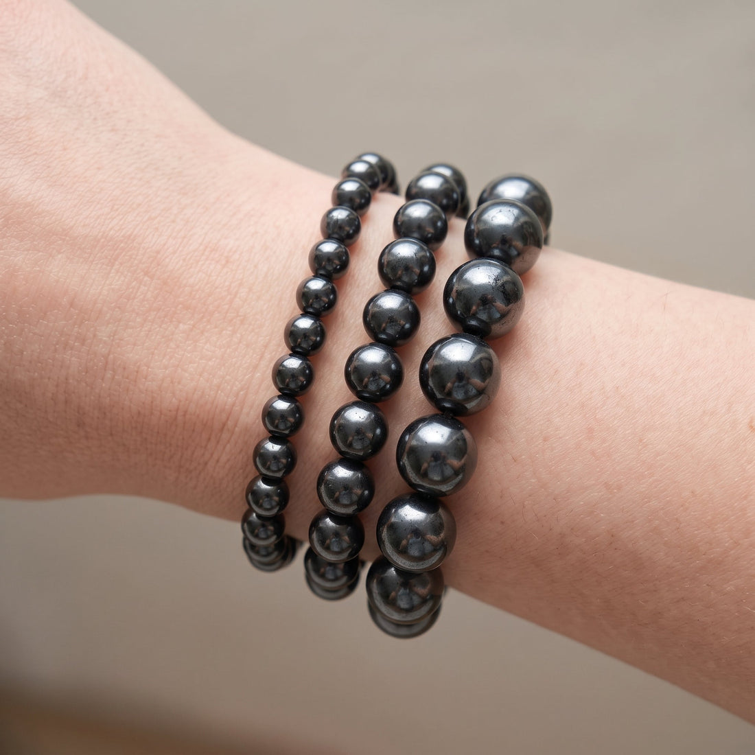 Trois bracelets en hématite de diamètres différents, portés ensemble au poignet - visuel provisoire
