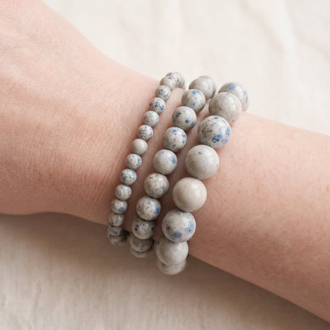 Trois bracelets en jaspe k2 de diamètres différents, portés ensemble au poignet - visuel provisoire
