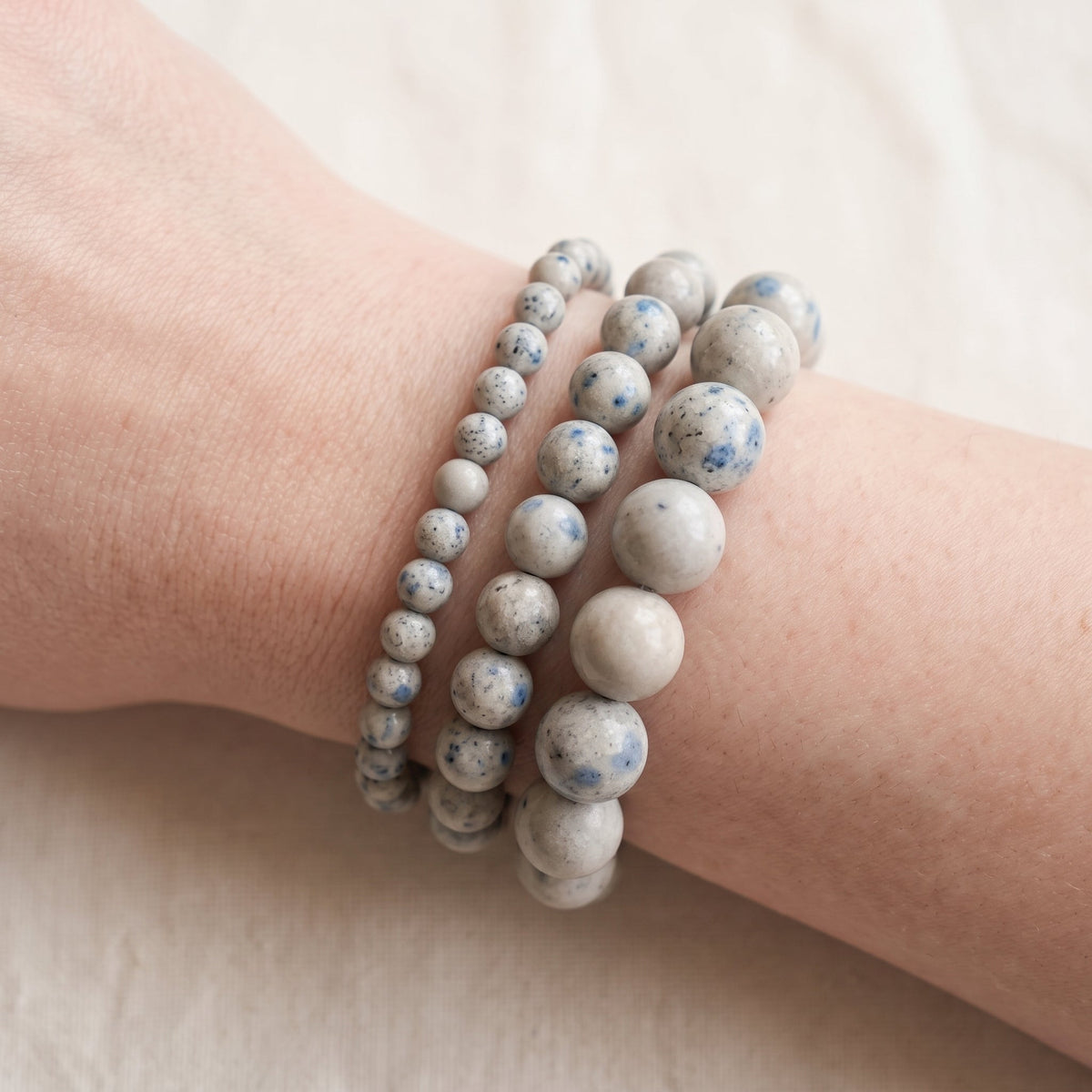 Trois bracelets en jaspe k2 de diamètres différents, portés ensemble au poignet - visuel provisoire