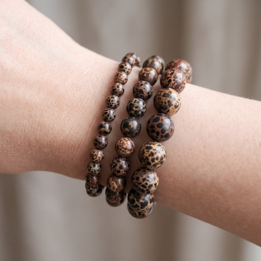 Trois bracelets en jaspe léopard de diamètres différents, portés ensemble au poignet - visuel provisoire