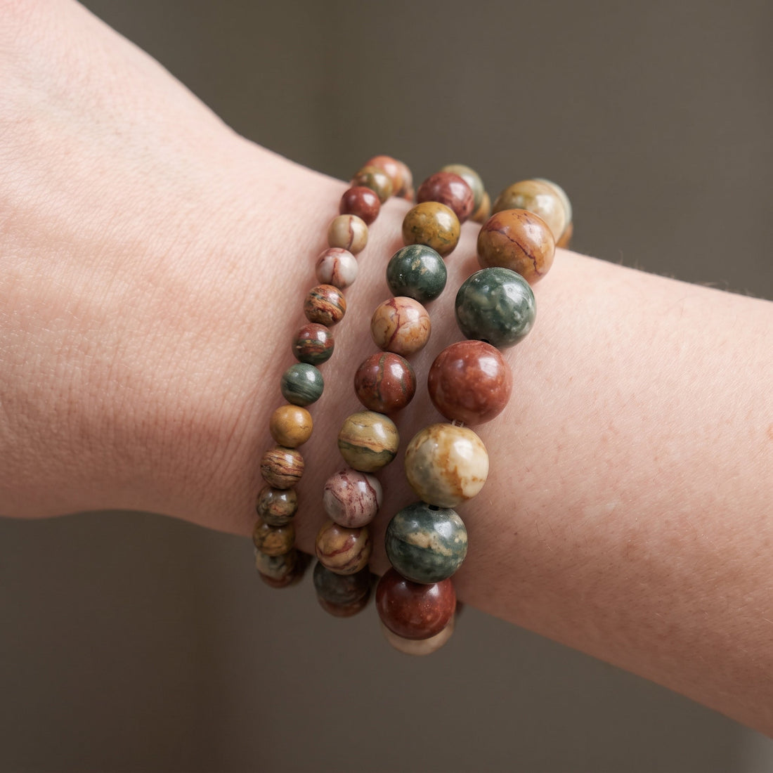 Trois bracelets en jaspe polychrome de diamètres différents, portés ensemble au poignet - visuel provisoire
