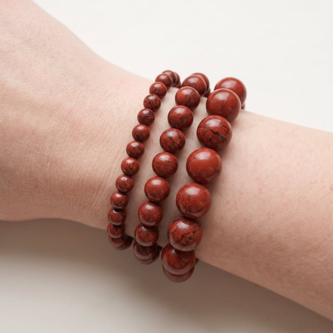 Trois bracelets en jaspe rouge de diamètres différents, portés ensemble au poignet - visuel provisoire