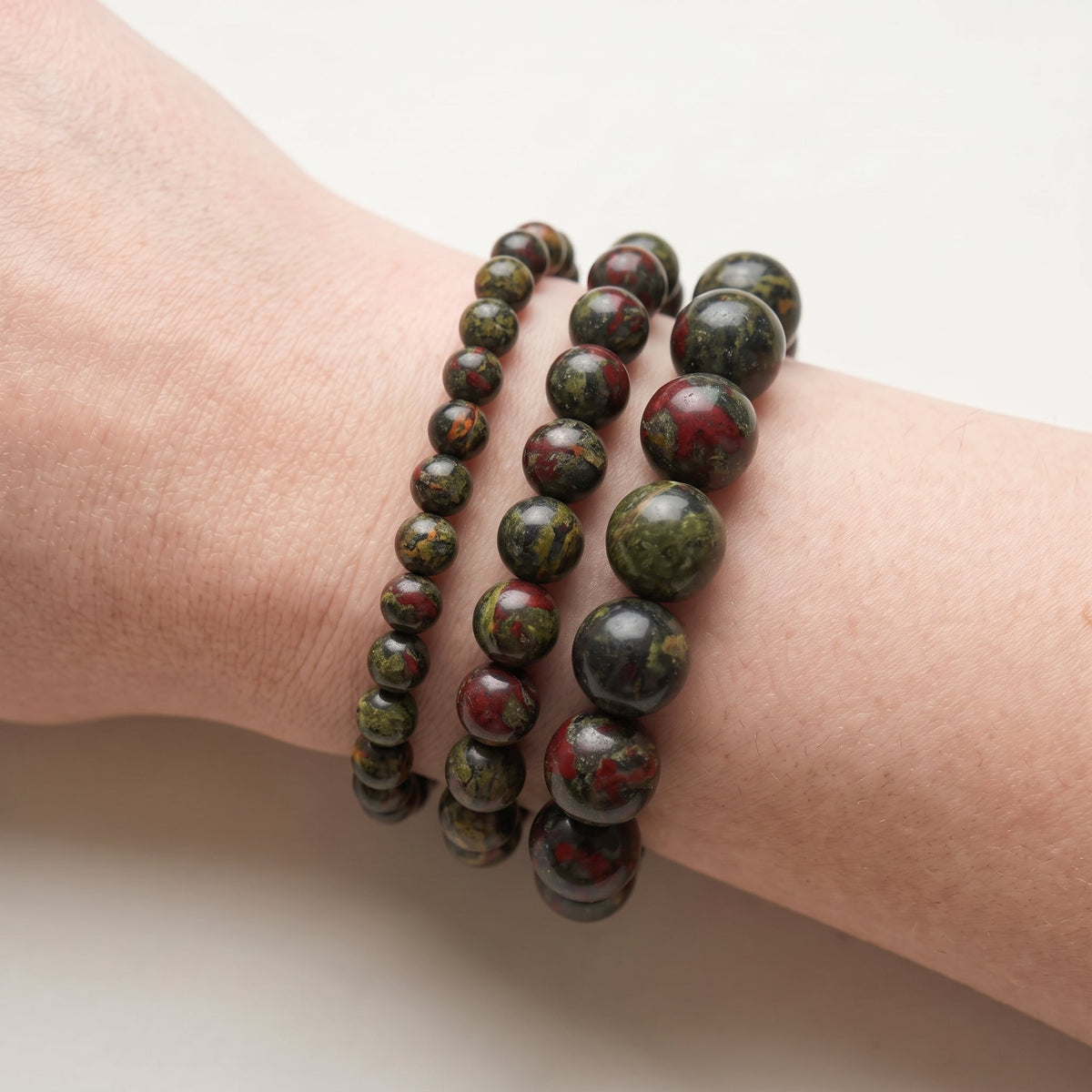 Trois bracelets en jaspe sang de dragon de diamètres différents, portés ensemble au poignet - visuel provisoire