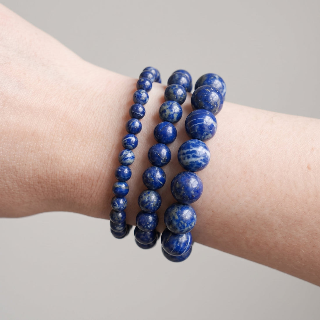 Trois bracelets en lapis-lazuli de diamètres différents, portés ensemble au poignet - visuel provisoire