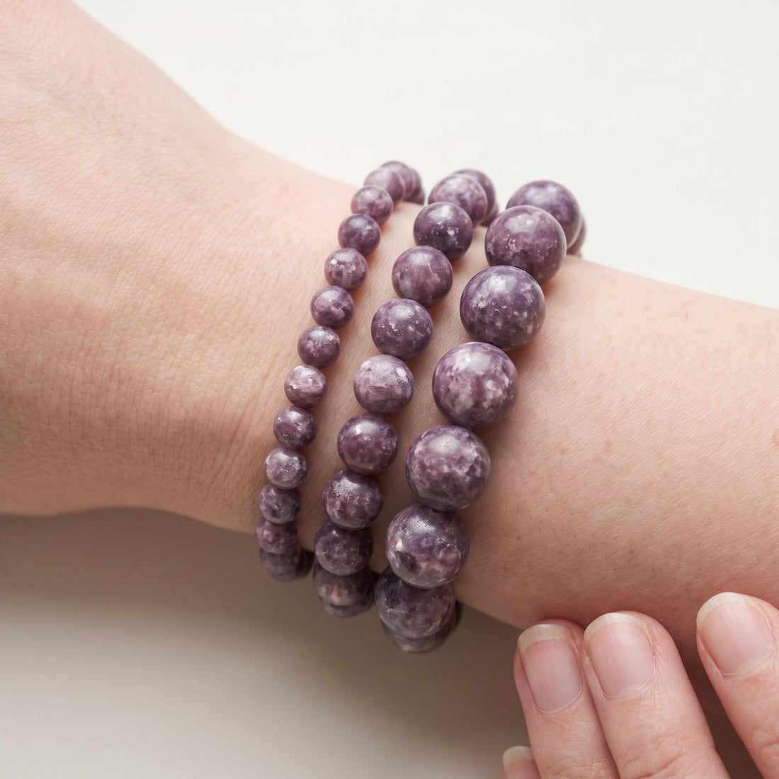 Trois bracelets en lépidolite de diamètres différents, portés ensemble au poignet - visuel provisoire
