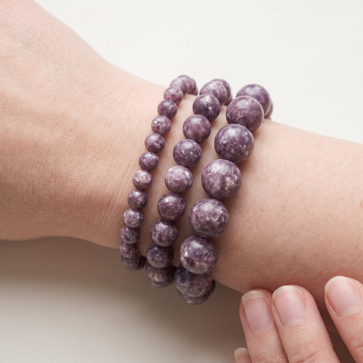 Trois bracelets en lépidolite de diamètres différents, portés ensemble au poignet - visuel provisoire