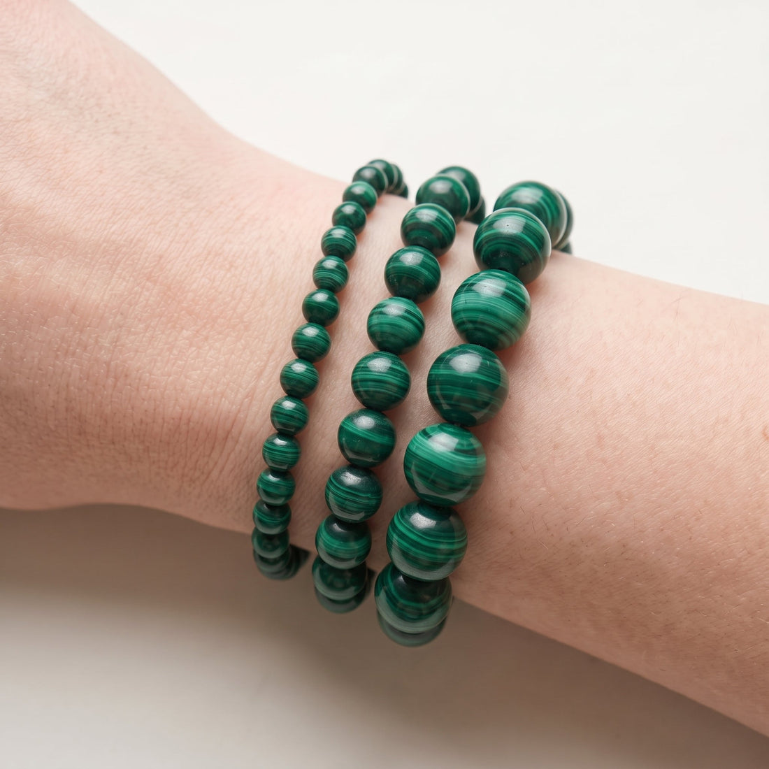 Trois bracelets en malachite de diamètres différents, portés ensemble au poignet - visuel provisoire