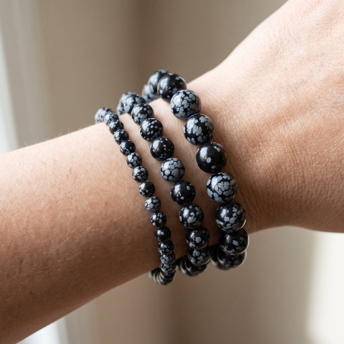 Trois bracelets en obsidienne neige de diamètres différents, portés ensemble au poignet - visuel provisoire