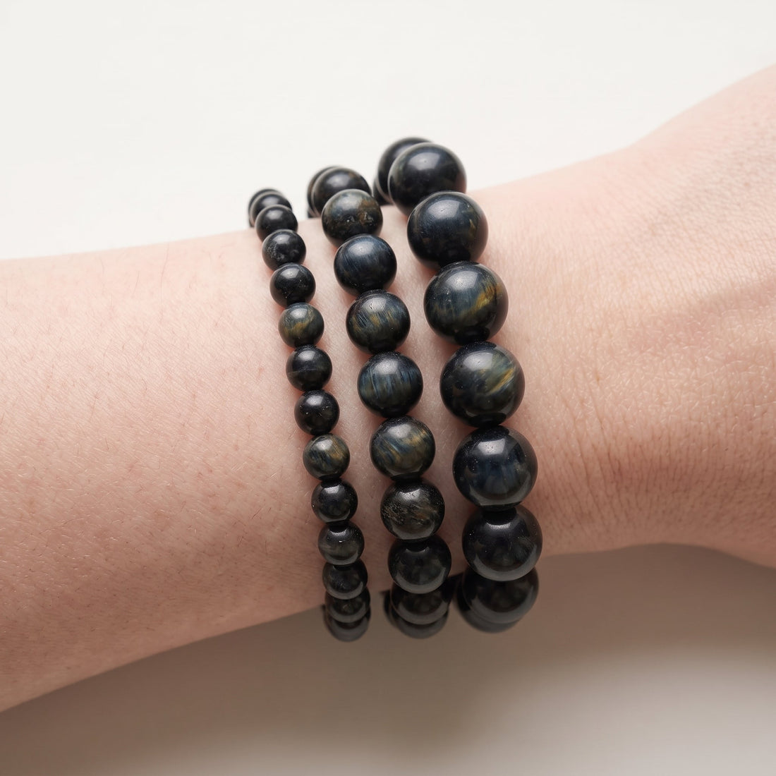 Trois bracelets en œil de faucon de diamètres différents, portés ensemble au poignet - visuel provisoire
