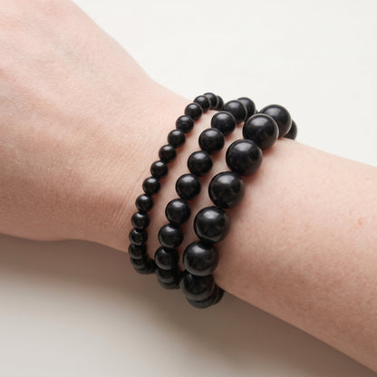 Trois bracelets en onyx de diamètres différents, portés ensemble au poignet - visuel provisoire