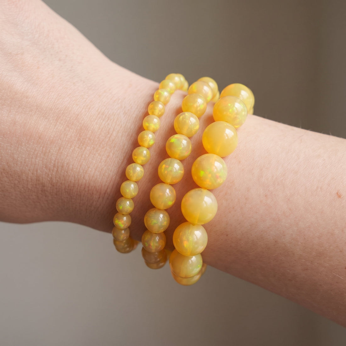 Trois bracelets en opale jaune de diamètres différents, portés ensemble au poignet - visuel provisoire