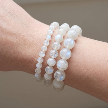 Trois bracelets en pierre de lune blanche de diamètres différents, portés ensemble au poignet - visuel provisoire
