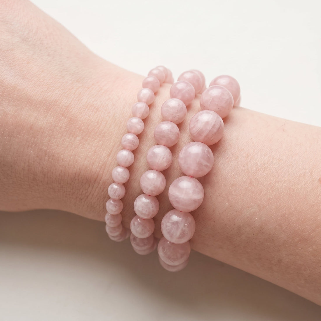 Trois bracelets en pierre de lune rose de diamètres différents, portés ensemble au poignet - visuel provisoire