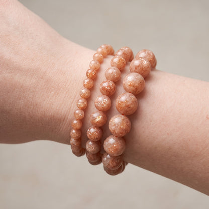 Trois bracelets en pierre de soleil de diamètres différents, portés ensemble au poignet - visuel provisoire
