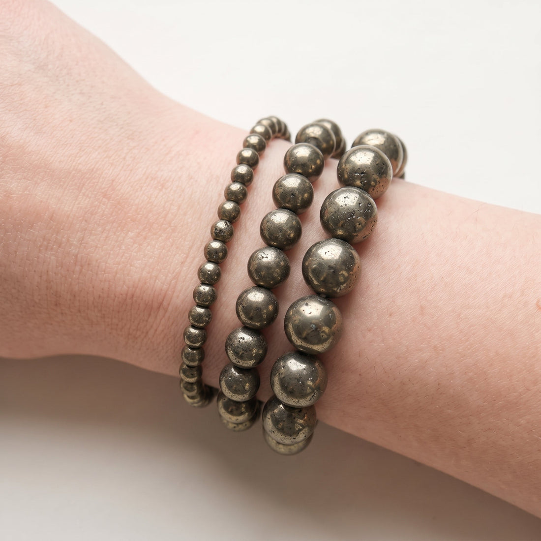 Trois bracelets en pyrite de diamètres différents, portés ensemble au poignet - visuel provisoire